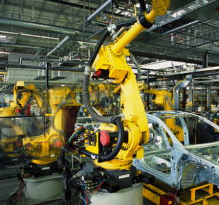 yellow robots welding cars in a production line